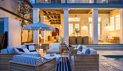 Outdoor area at night with lights illuminated with patio furniture arranged in a circle next to the pool.