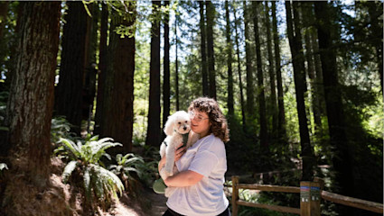 A woman holds a little white dog in Portland’s green dog park, making the city a laid-back choice for pet-friendly weekend getaways.