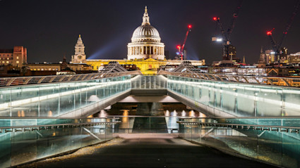A view of London's Millennium Bridge and St. Paul's Cathedral at night, representing the city's blend of history and modernity.