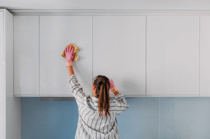 person cleaning kitchen cabinets