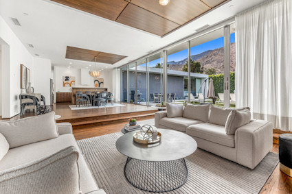 Floor-to-ceiling glass, warm wood and a sculptural fixture deliver calm, connected living in the desert.