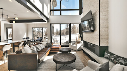 A modern living room with floor to ceiling windows framing the snow-covered slopes.