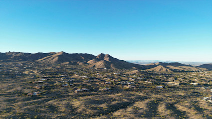 A sweeping landscape of Scottsdale's desert with distant homes nestled among cacti and rugged mountains, evoking the spacious, welcoming character of family-friendly desert living.