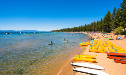Visitors enjoy sunbathing and paddleboarding at Lake Tahoe in summer.