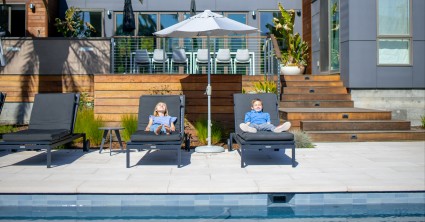 Kids in lounge chairs by residential pool.