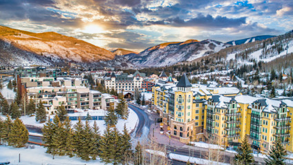 Aerial view of Vail in the snow with the sun setting behind the mountains.