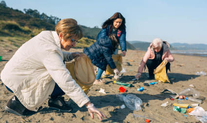 A group of people clean up trash on a beach while exploring what to do after retirement.