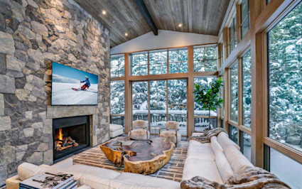 Elegant Vail home interior with vaulted ceilings, expansive windows, and a sleek fireplace, capturing the Vail vs. Aspen lifestyle.