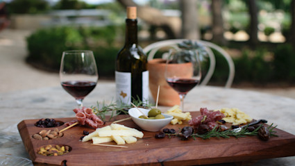 A rustic outdoor table set for a casual wine and charcuterie lunch, representing the relaxed summer experience at Napa’s renowned wineries.