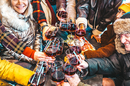 A group of people in snow gear raising their wine glasses to cheers.