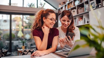 Two people research on their phone and computer about tenancy in common.