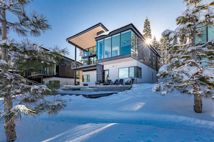Exterior of the home surrounded by snow and trees.