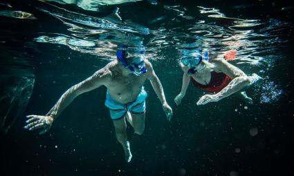 A couple enjoys snorkeling, one of the top hobbies for empty nesters.