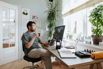 A man takes a coffee break after completing the perfect home office setup.