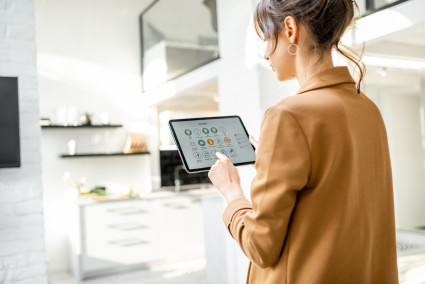 Homeowner manages home automation with a digital tablet in a modern, white living room.