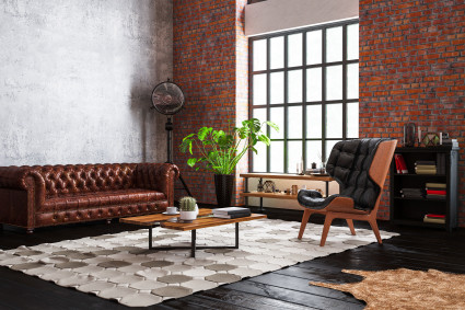 A living room with exposed brick is decorated in an industrial style, a popular type of interior design.