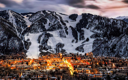 Downtown Aspen shops and restaurants at dusk beneath snowy Aspen Mountain