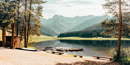 Lake with small dock with canoe's anchored and a vista of hazy mountains in the background. 