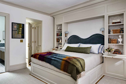 Contemporary bedroom with blue headboard, cream linens, and built-in shelving at Infinity by Pacaso home in Washington, D.C.