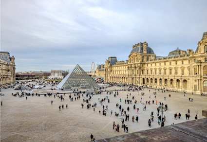 A stock image shows the Louvre surrounded by a crowd of people.