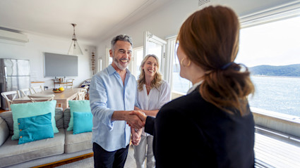 A couple shaking hands with a realtor as they buy their second home. 