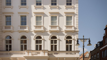 White stucco Mayfair townhouse exterior with classical columns and arched windows, from the Charles Street listing