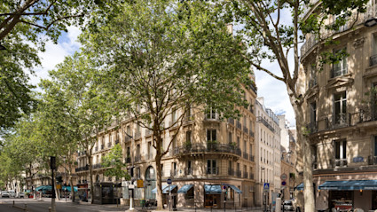 Tree-lined Parisian street corner with Haussmann buildings and cafes, desktop crop, Saint Germain listing