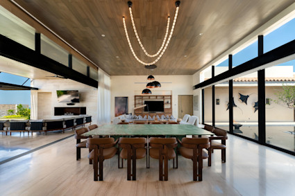 A dining room in Los Cabos featuring a wall of windows and wooden ceiling, capturing the ambiance of enjoying local Mexican cuisine.