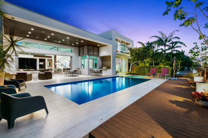 Outdoor deck and pool of a white, luxury home