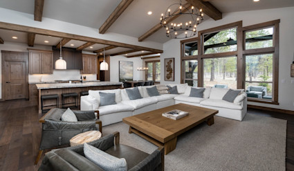 Living area with large white sectional couch and kitchen with large island with stainless steel appliances.