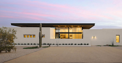 An image of a contemporary house rests under the evening sky, displaying one of the many types of houses available to home buyers.