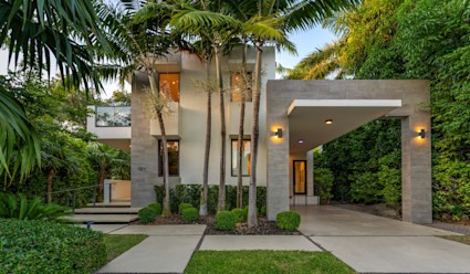Exterior of the Venetian luxury home with manicured shrubs and palm trees.