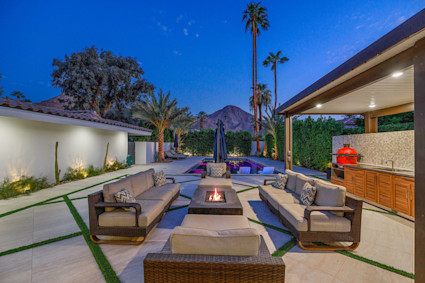 Twilight patio with fire pit and mountain backdrop in Palm Desert, CA, illustrating the inviting outdoor living spaces and dramatic desert scenery that define these luxury homes.