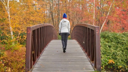 A woman walks over a bridge at Stowe, Vermont, a great destination for pet-friendly vacations thanks to its parks and trails.
