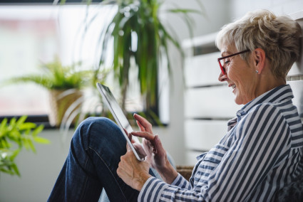 Senior woman reading on digital tablet at home. 