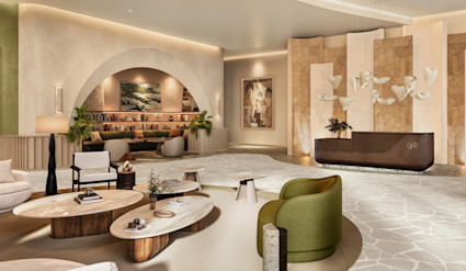 Sculptural residential lobby with arched reading nook, organic stone coffee tables, green lounge chairs, and a branded concierge desk.