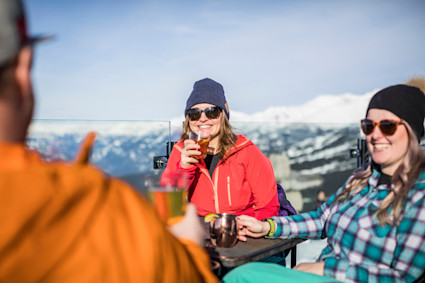 A trio enjoying cocktails on top of a snowy mountain.