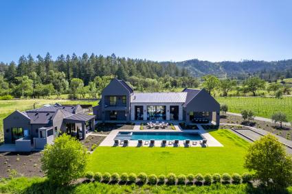 a house with a pool in the middle of a green field