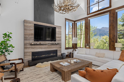 A luxurious living room with a fireplace and panoramic mountain views in Telluride, CO, embodying the spirit of a private mountain retreat.