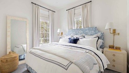 A bedroom with a white bed and blue and white luxury bedding

