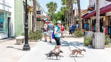 A woman walks her dogs through the shopping district of St. Augustine, Florida, showing it’s a great destination for pet-friendly vacations. 