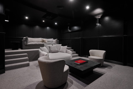 A custom home cinema with elevated viewing area and theater lighting. 