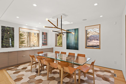 A light-filled dining area with warm wood and refined lighting reflects mountain calm suited to winter gatherings.