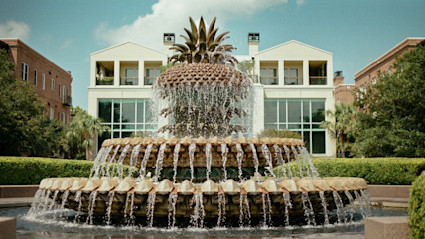 Iconic Pineapple Fountain in Charleston, SC, framed by palm trees and lush landscaping, symbolizing the welcoming hospitality and signature flavors of Lowcountry gatherings in a picturesque fall setting.