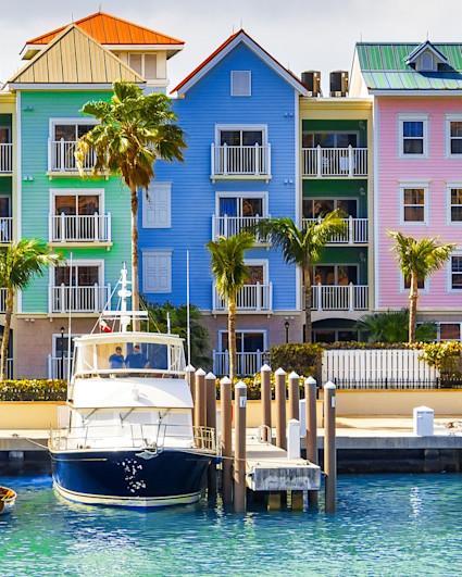 Costal harbor with several boats anchored in front of a row of colorful buildings. 