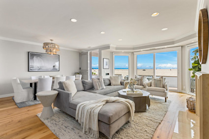 Balboa Sands showcases Newport Beach’s approach to luxury home design, highlighting a sunlit living room with modern finishes, wall-to-wall windows, and a statement chandelier.
