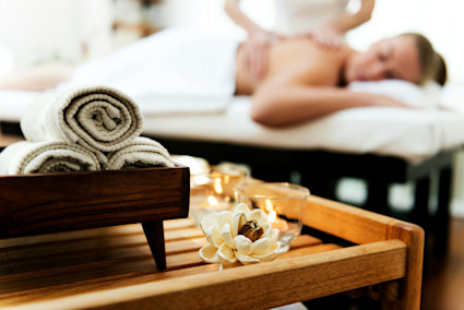 Towels and candles on a table by a woman getting a massage.