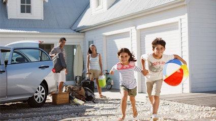 Two kids run for the beach as their parents unload the car at their vacation property, having answered the question for themselves, “Are timeshares worth it?”