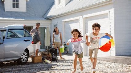Two kids run for the beach as their parents unload the car at their vacation property, having answered the question for themselves, “Are timeshares worth it?”