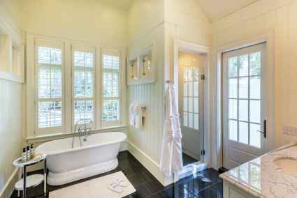 An en-suite bathroom with a white bath tub and sink, featuring modern fixtures and a clean design